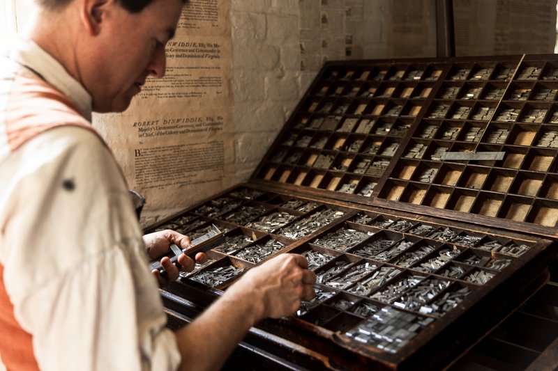 A photo of a printmaker looking for letters to set type.