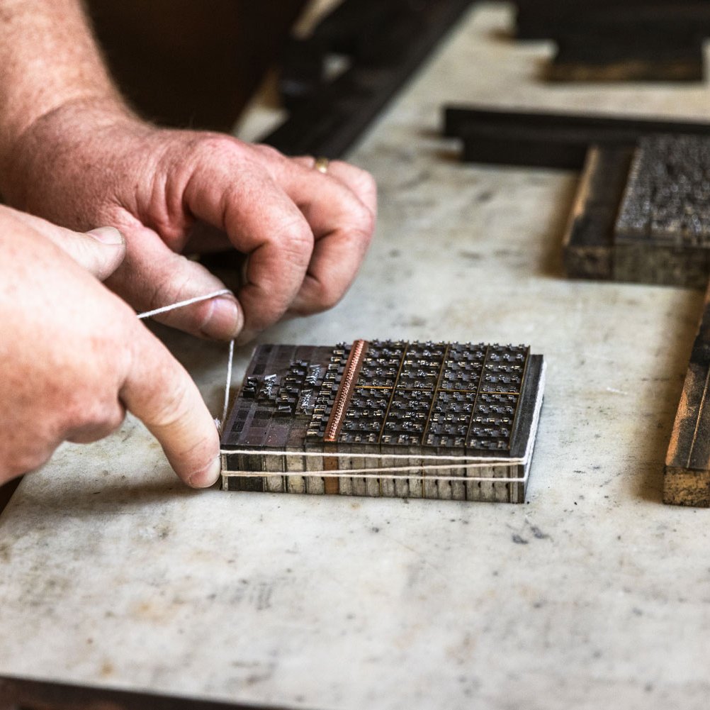 A photo of a printmaker setting type.