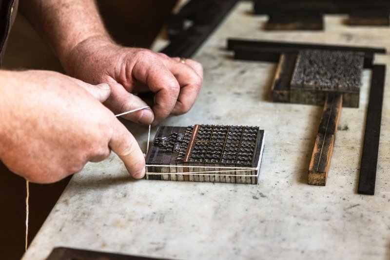 A photo of a printmaker setting type.