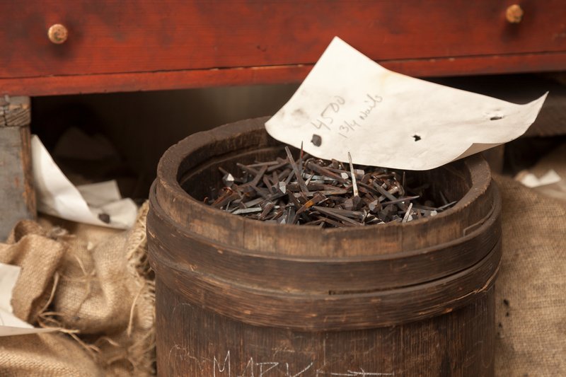 A barrel of nails made by the blacksmiths with a piece of paper sitting on top.