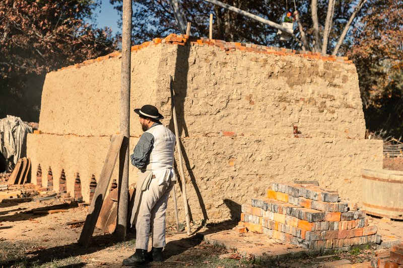 A photo of a brickmaker in the brickyard by the brick kiln