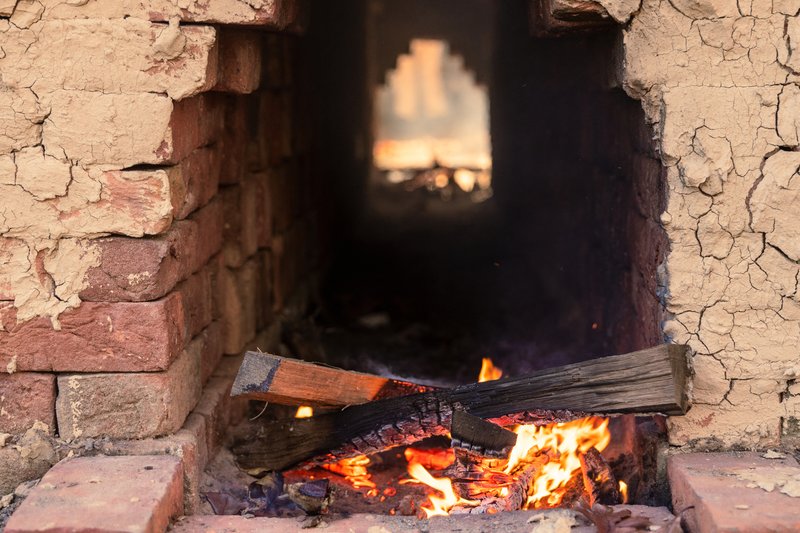 A photo of the inside of the brick kiln with some wood burning.