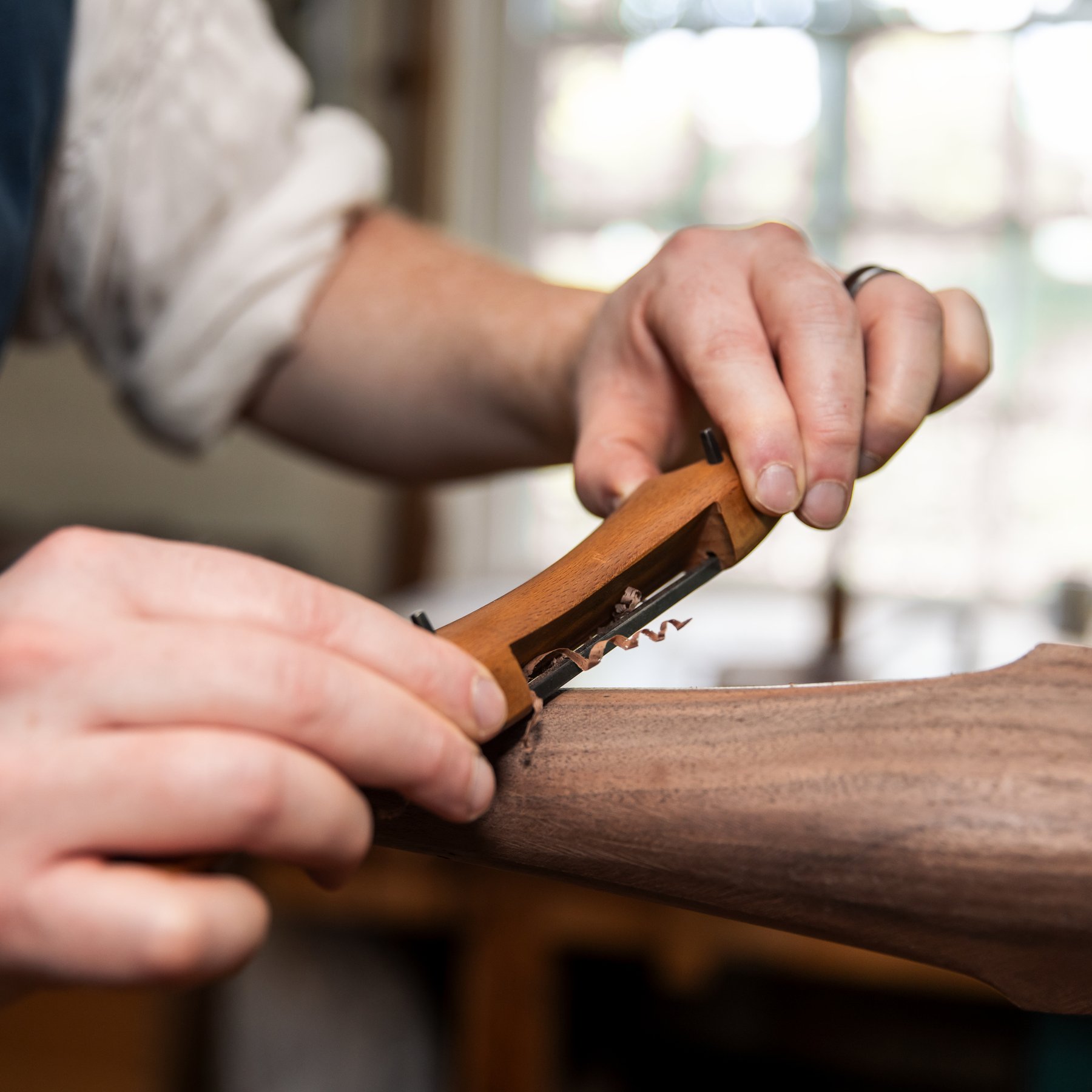 A close up photo of a cabinetmaker shaving the wood on a dressing table.