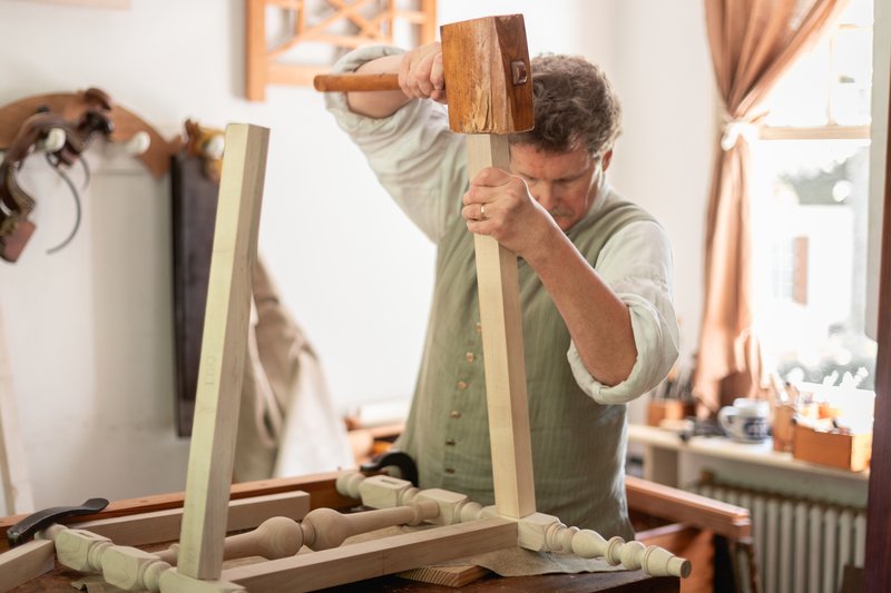 A photo of a joiner helping make a piece of furniture for the Bray School.