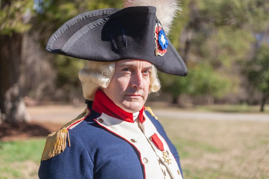 An interpreter dressed as Marquis De Lafayette smiles at the camera.