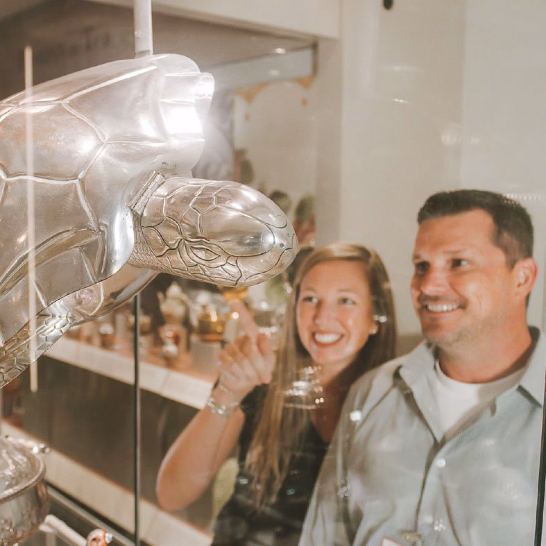 A couple at the Art Museums of Colonial Williamsburg examine a silver turtle on display