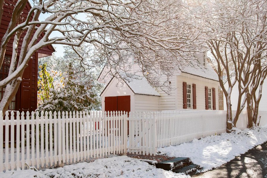 Sun shines through the trees over the snowy roofs of Colonial Williamsburg