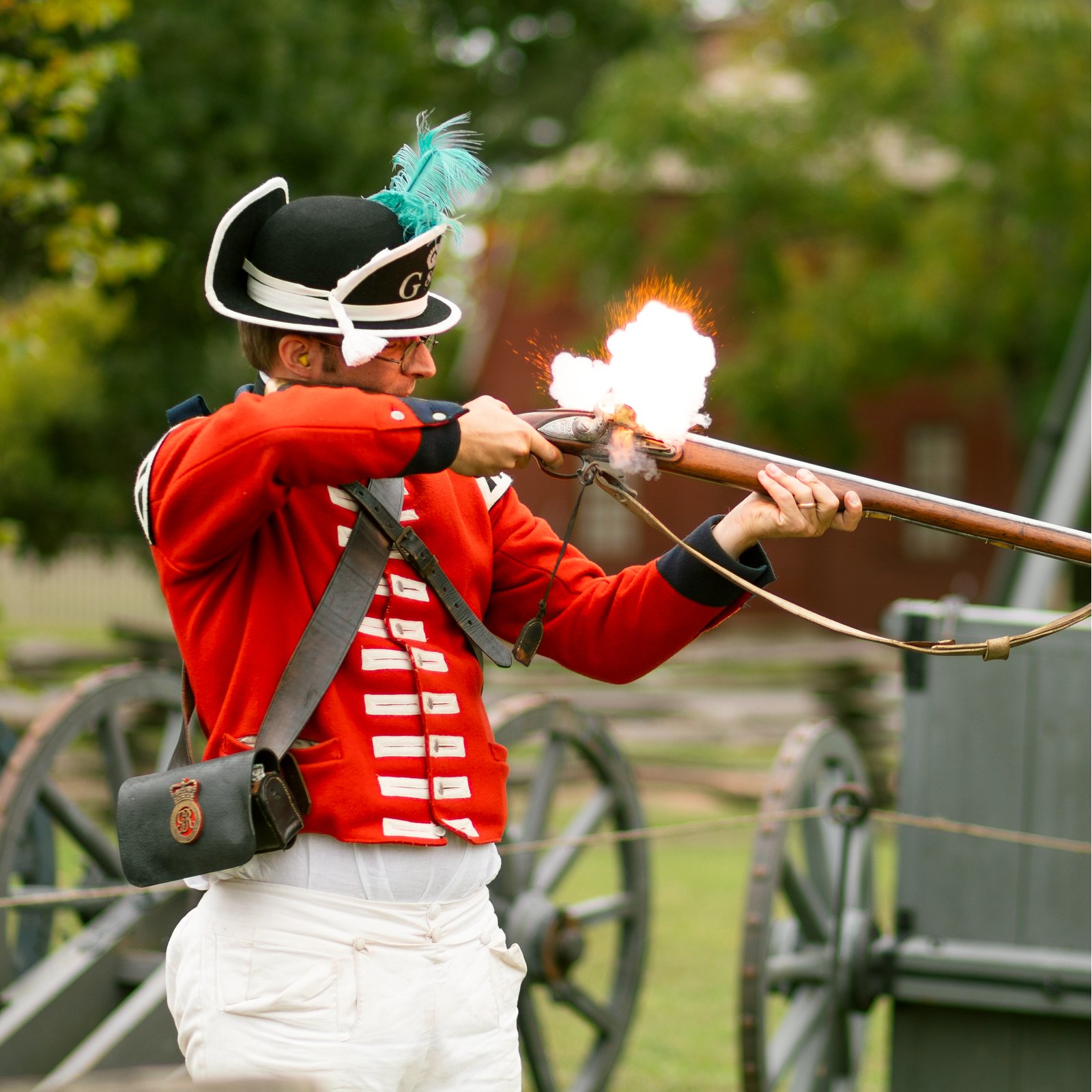 A costumed interpreter fires a gun in Colonial Williamsburg's Historic Area.