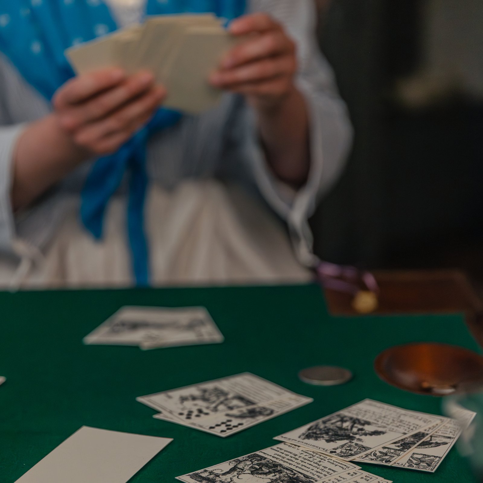 A costumed interpreter plays cards at a table.
