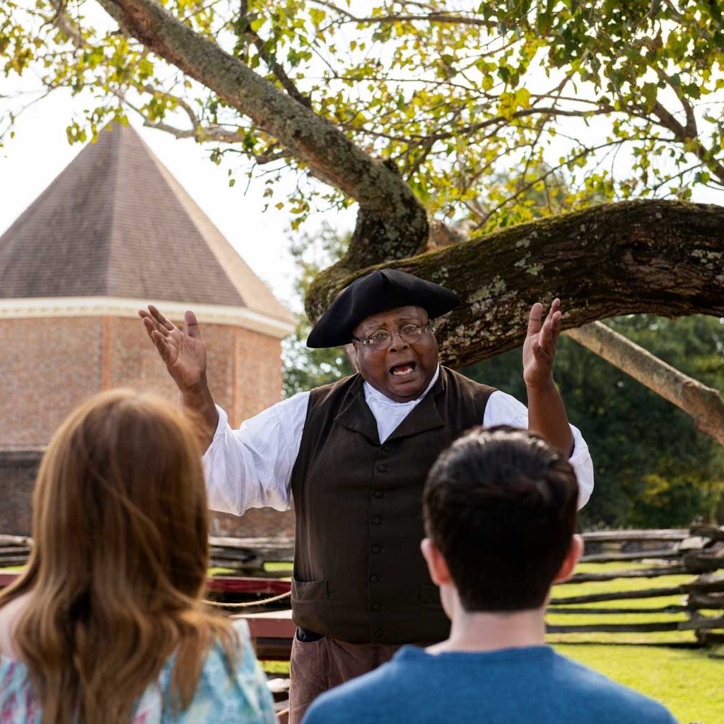 An interpreter dressed as Gowan Pamphlet speaks to a tour group.