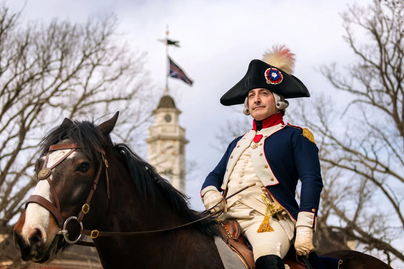 An interpreter dressed as Marquis de Lafayette sits atop a horse in front of the Capitol building.