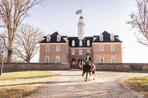 An interpreter dressed as Marquis de Lafayette sits atop a horse in front of the Capitol building.