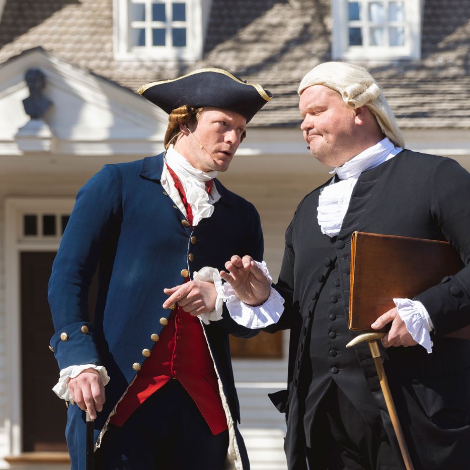 Interpretors dressed as George Wythe and Thomas Jefferson speak to one another in front of the Raleigh Tavern.